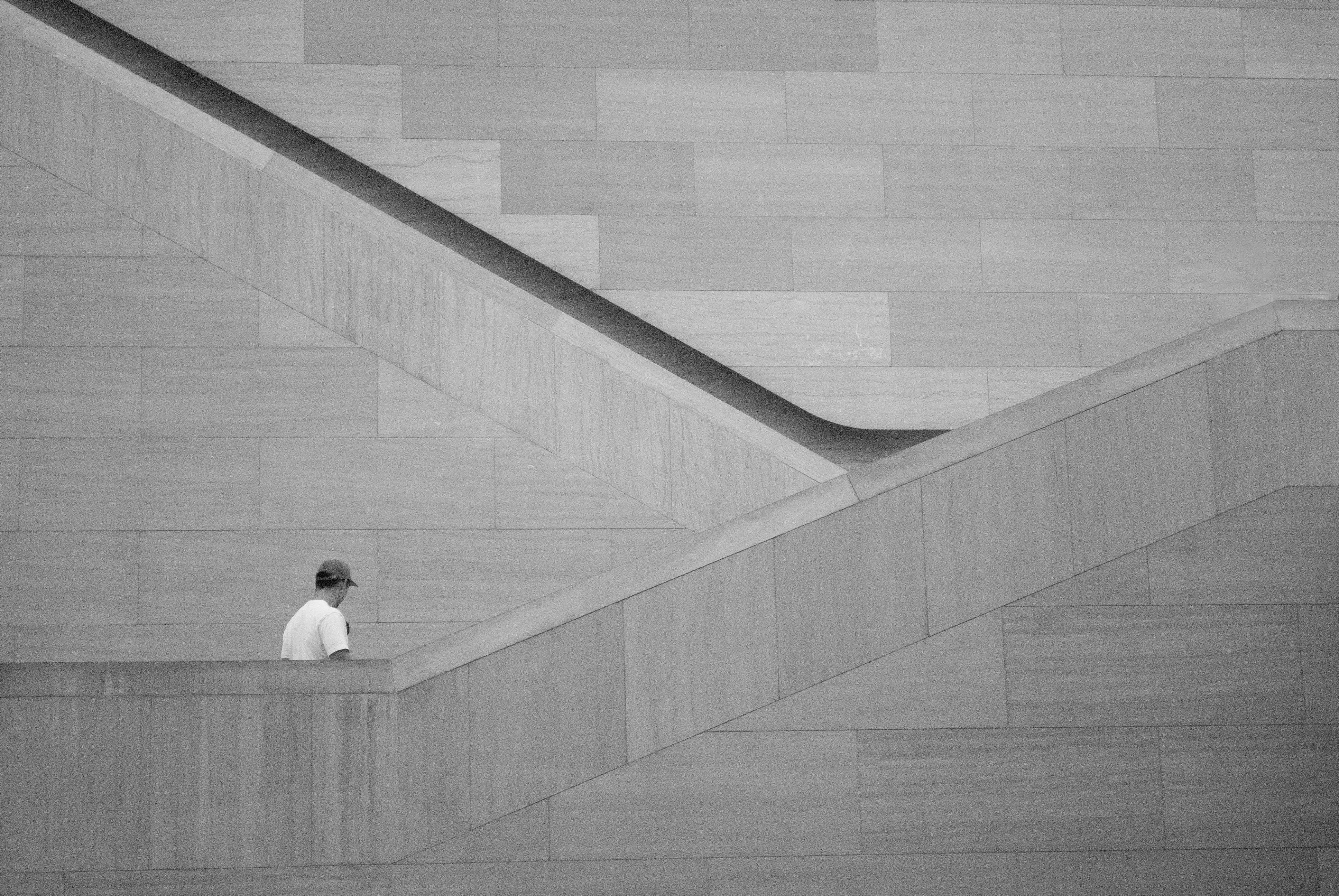 Person walking on a concrete parapet beside a staircase