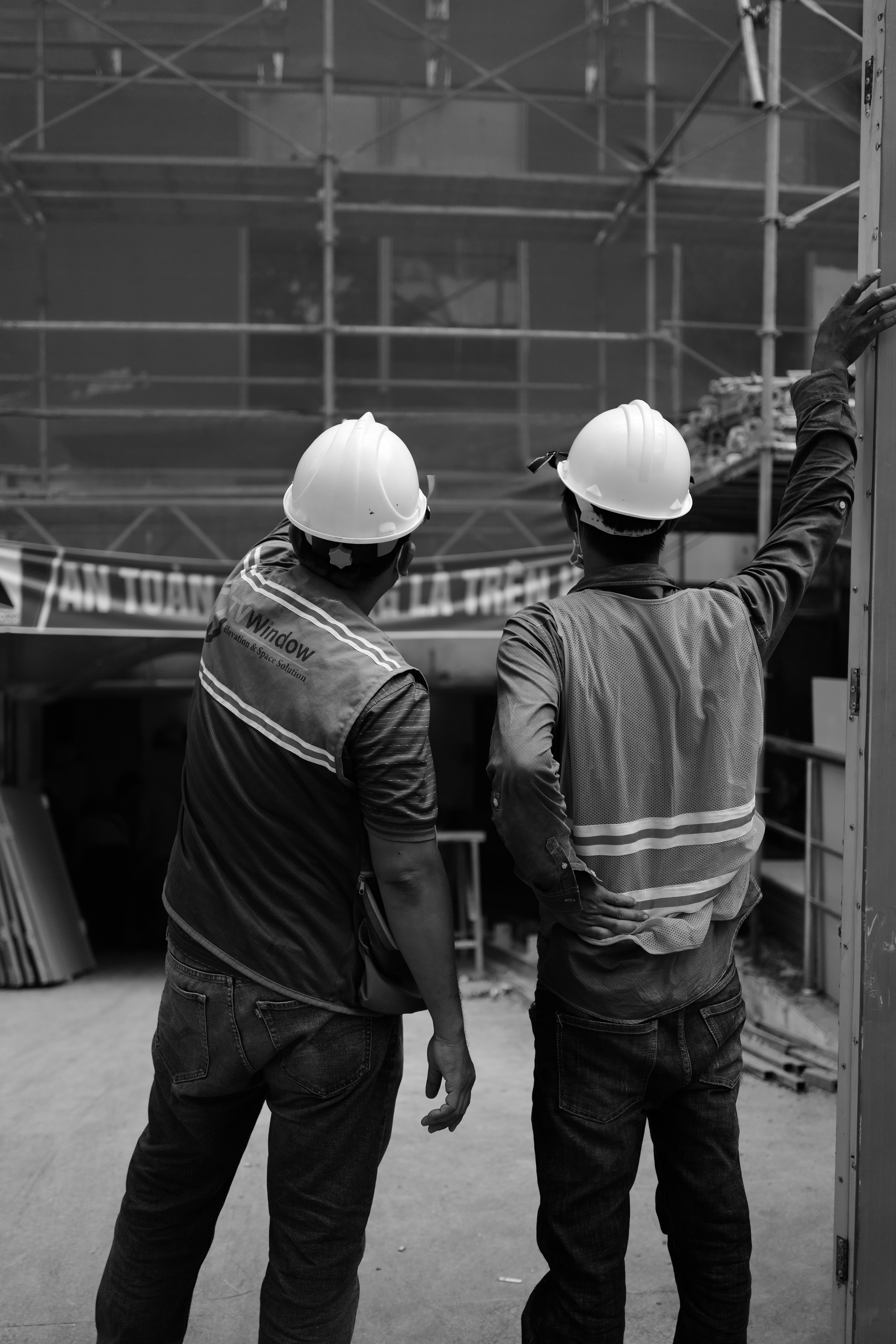Two construction workers in hard hats reviewing scaffolding on site